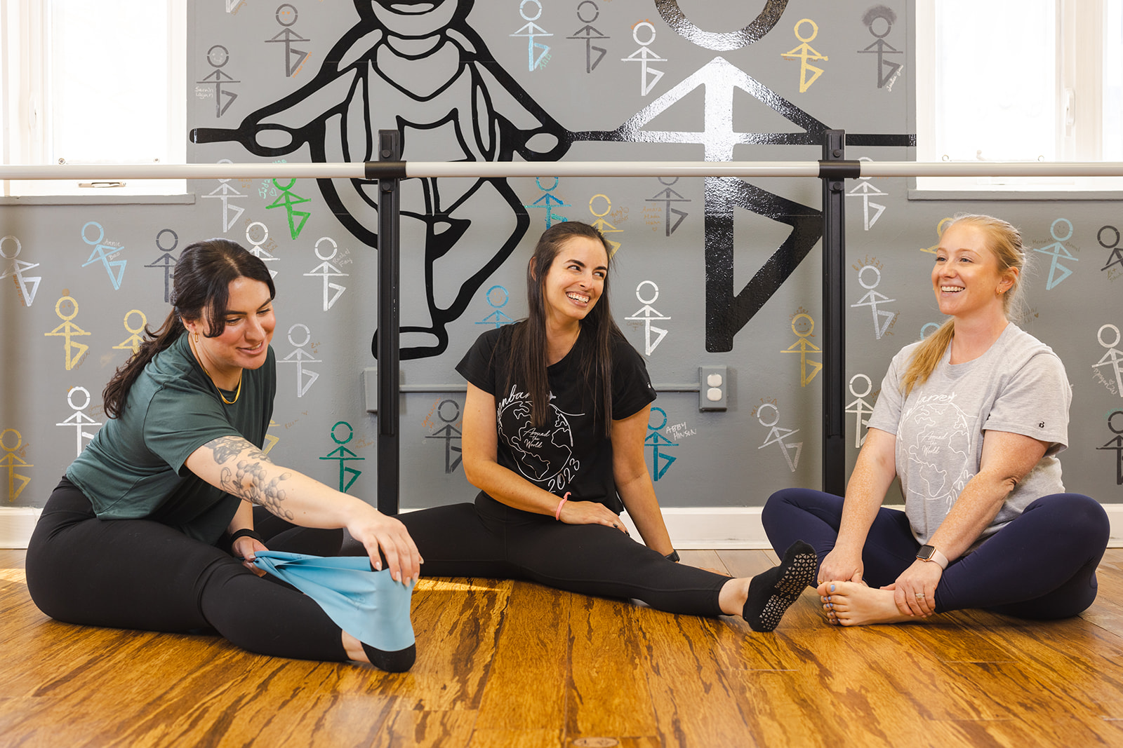 women in barre stretch class using  stretch muscles on balanced body yoga mats